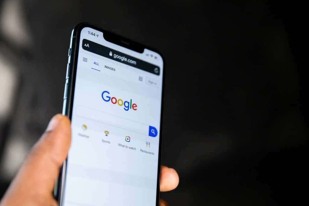 Hand holding a smartphone showing Google search